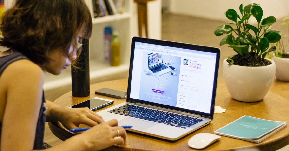 A person working alone and focused at a quiet desk with a laptop