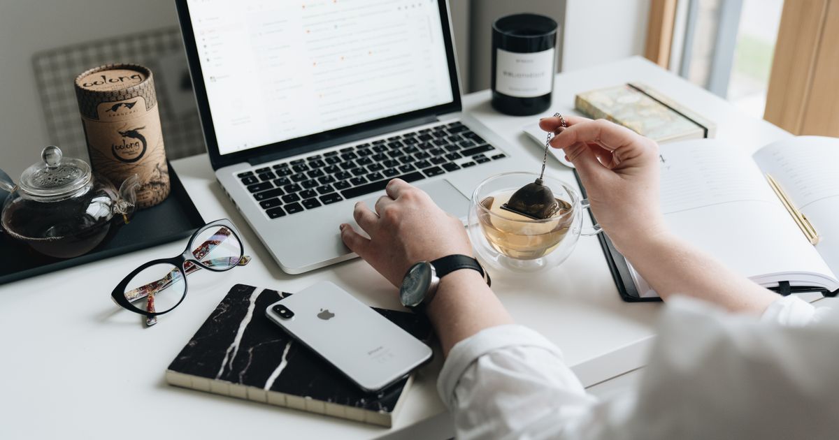 A tidy home-office desk with a laptop, phone and coffee