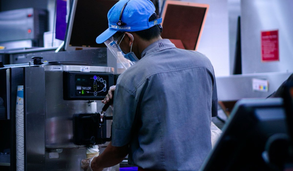 Fast food crew member taking a drive-thru order on a headset while working the front counter