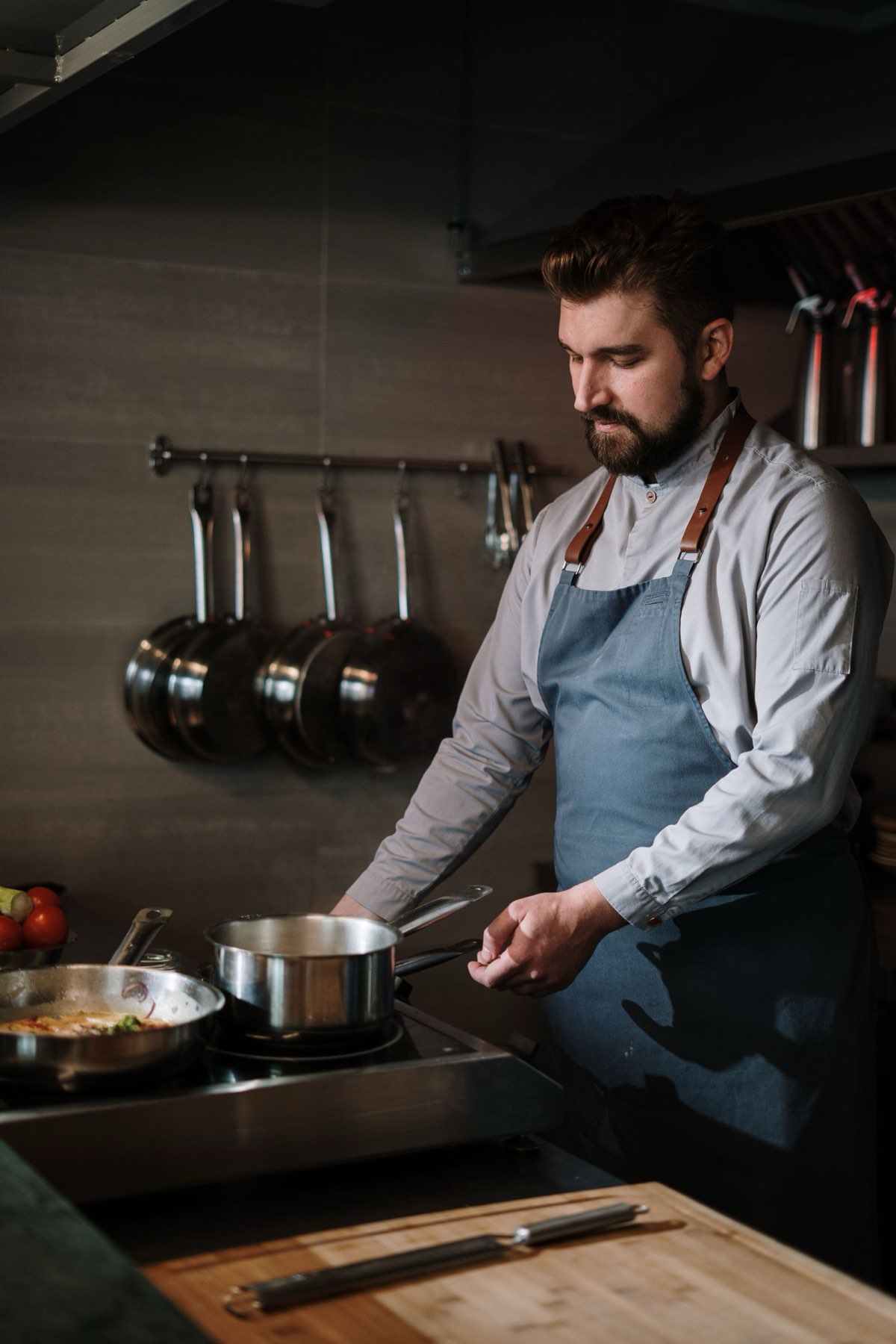 Line cook plating food in a busy restaurant kitchen