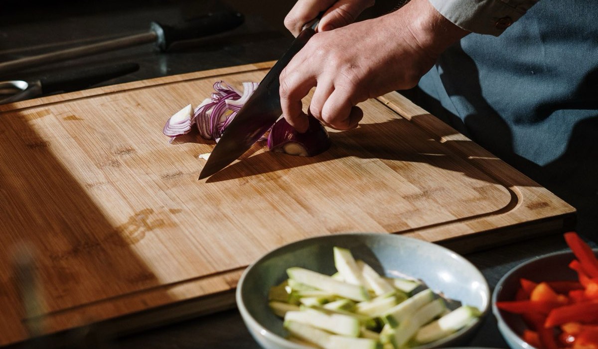 Prep cook dicing vegetables and organising mise en place at a stainless-steel kitchen station