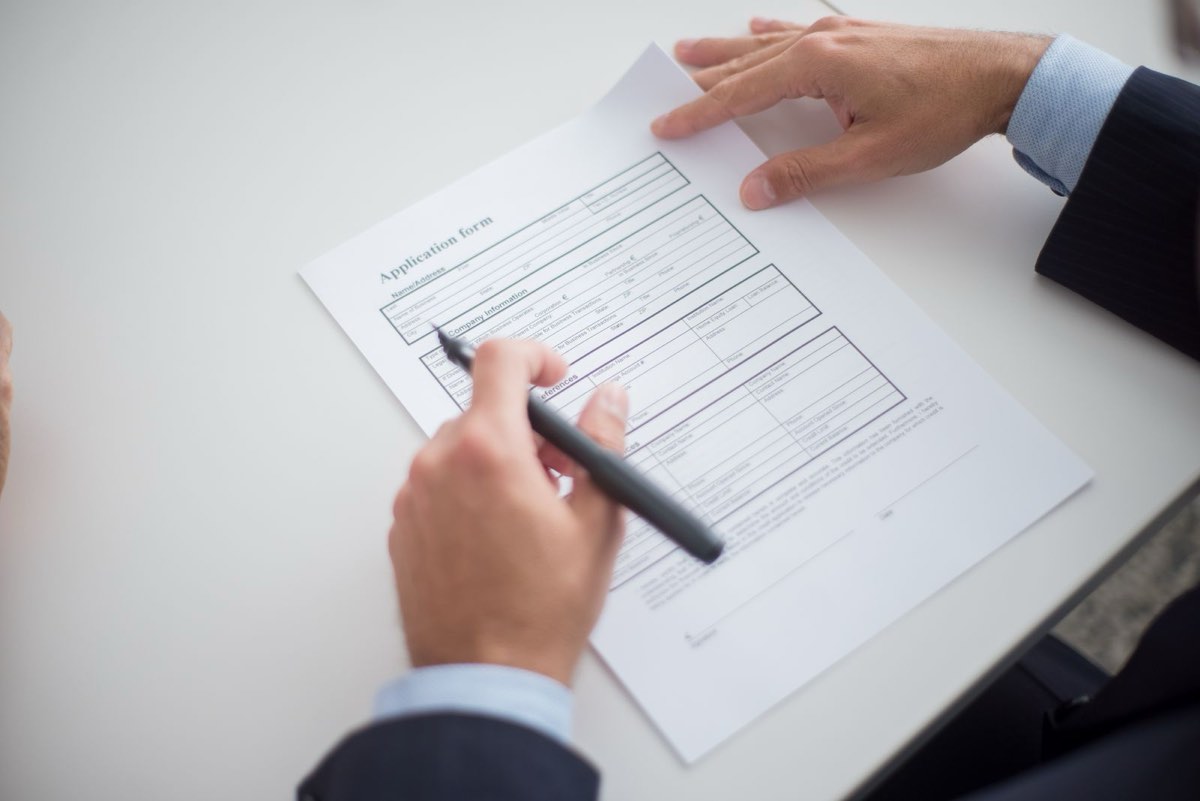 Hiring manager marking up a printed resume with a red pen at a desk