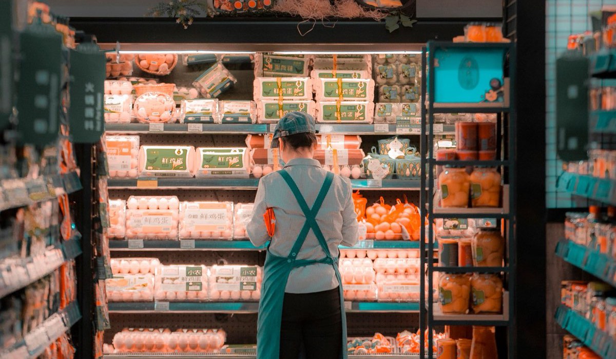 Retail stocker replenishing shelves and scanning inventory with a handheld RF scanner in a store aisle